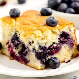 a slice of Blueberry Cake topped with blueberries on a plate