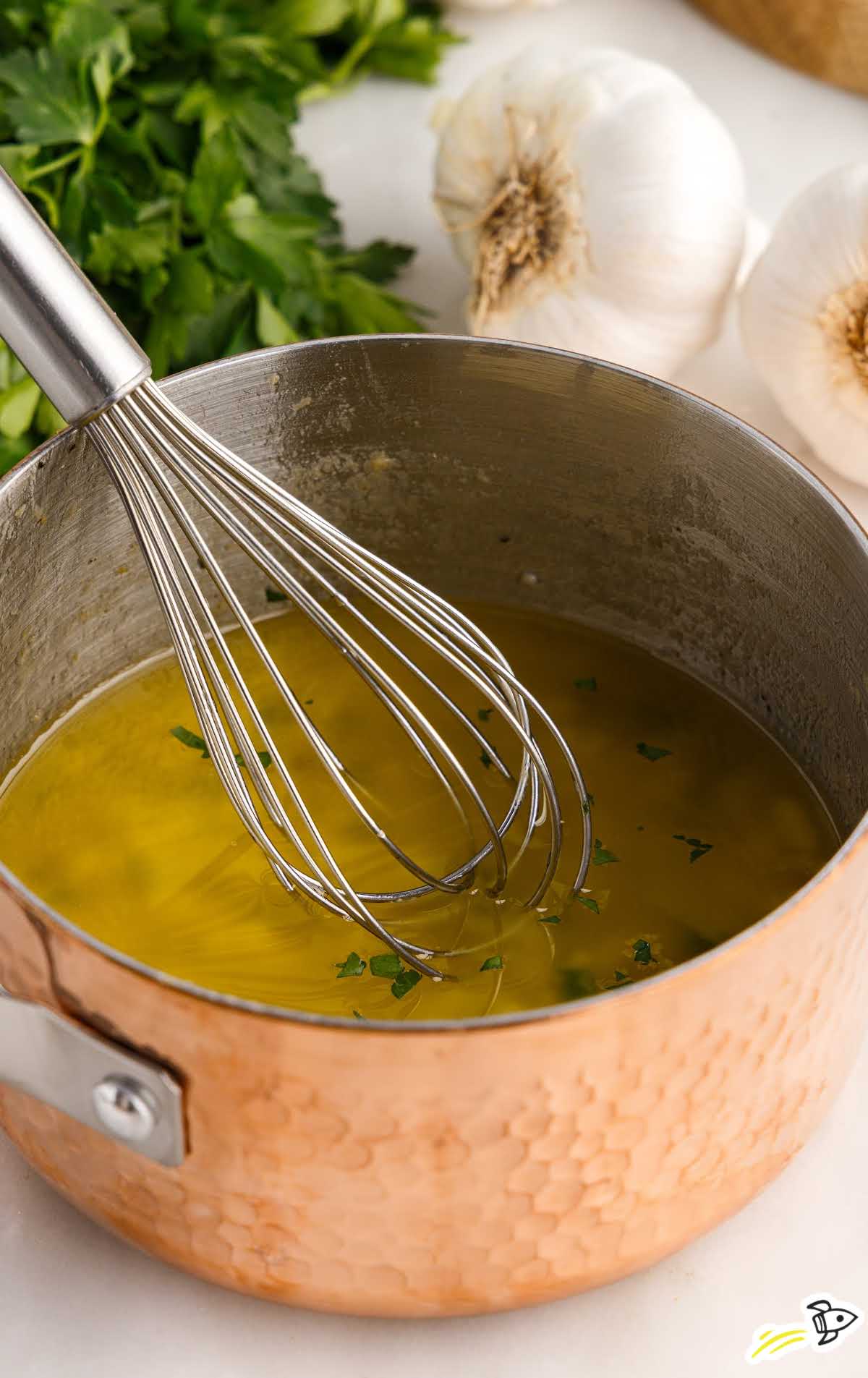 a close up shot of Garlic & Butter Sauce being whisked in a pot 