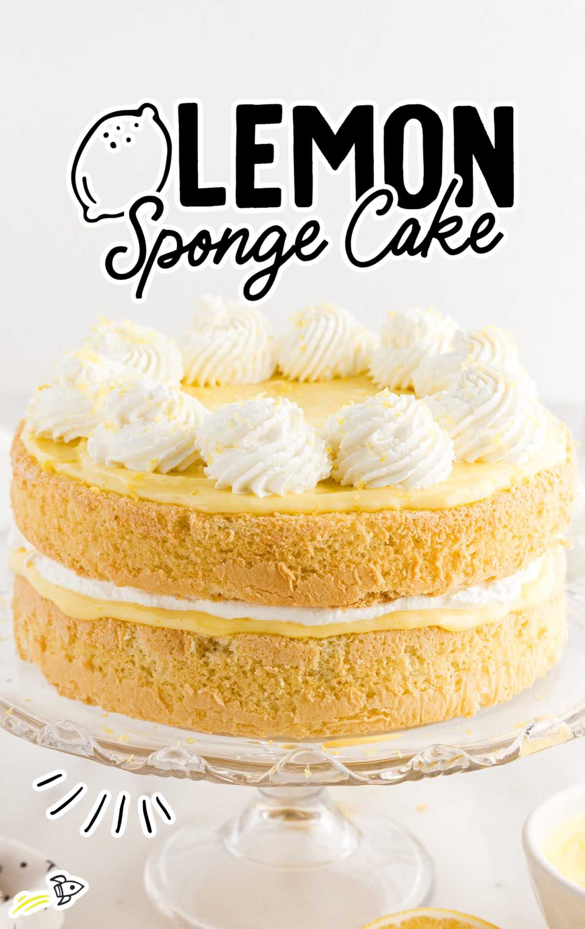 close up shot of a lemon sponge cake topped with whipped cream on a cake stand