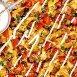 overhead shot of Loaded Fries on a baking tray with a side of sour cream