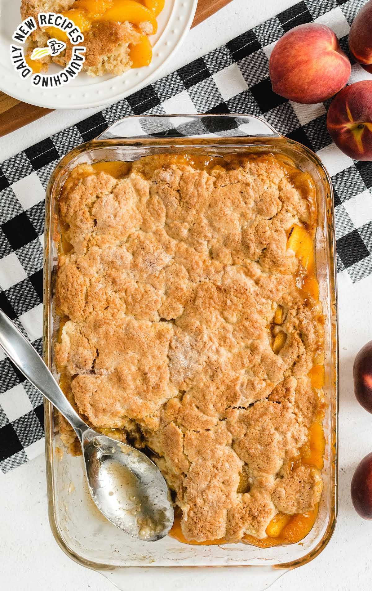 Peach Cobbler in a baking dish with a slice taken out with a spoon