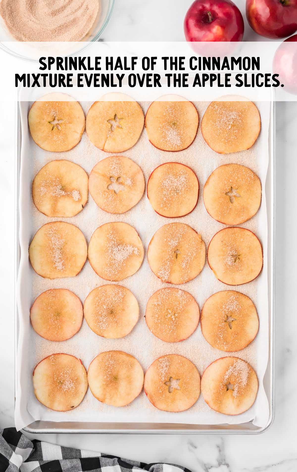 cinnamon mixture sprinkled over the apple slices on a baking sheet