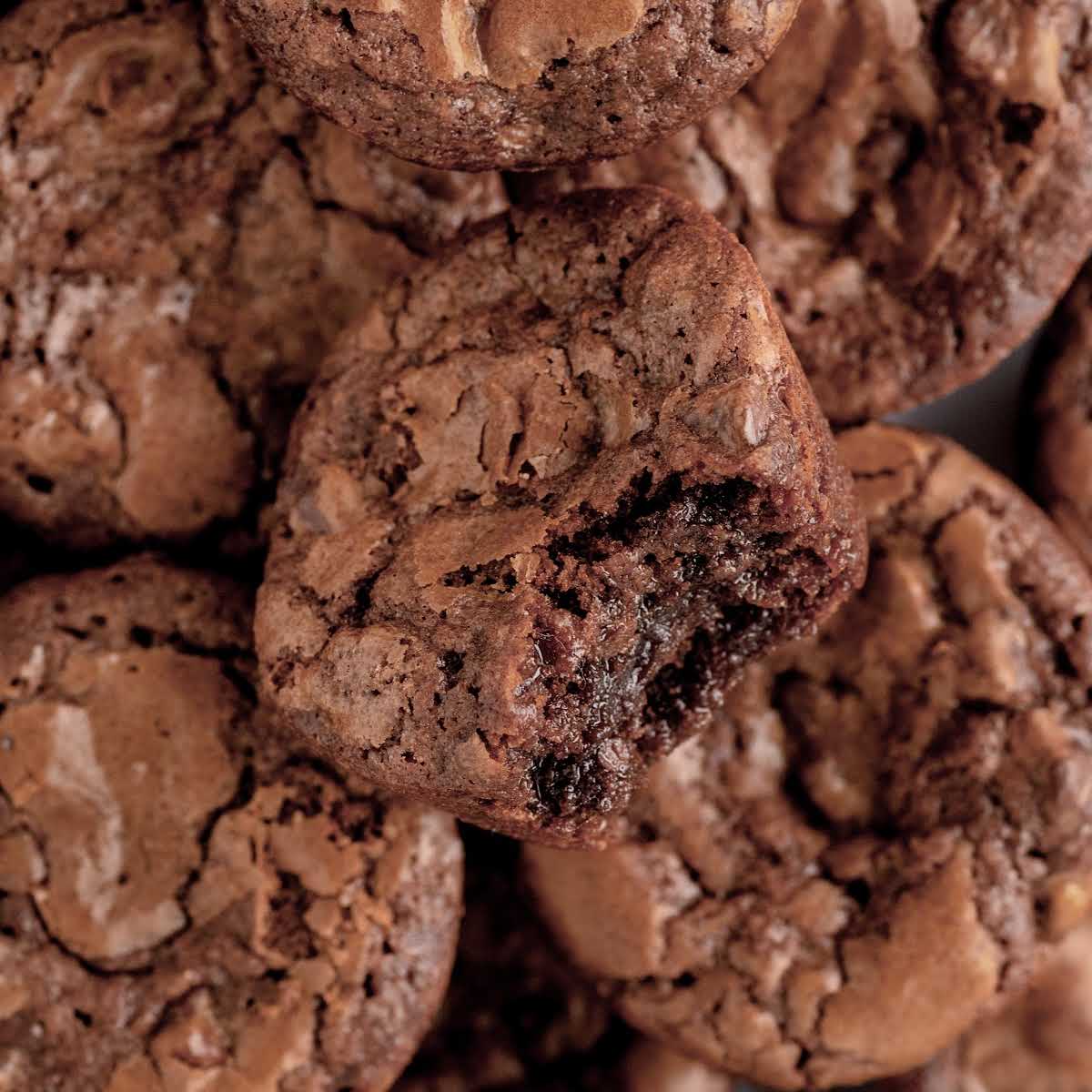close up shot of Brownie Bites stacked on top of each other with a bite taken off of the top of the brownie bite