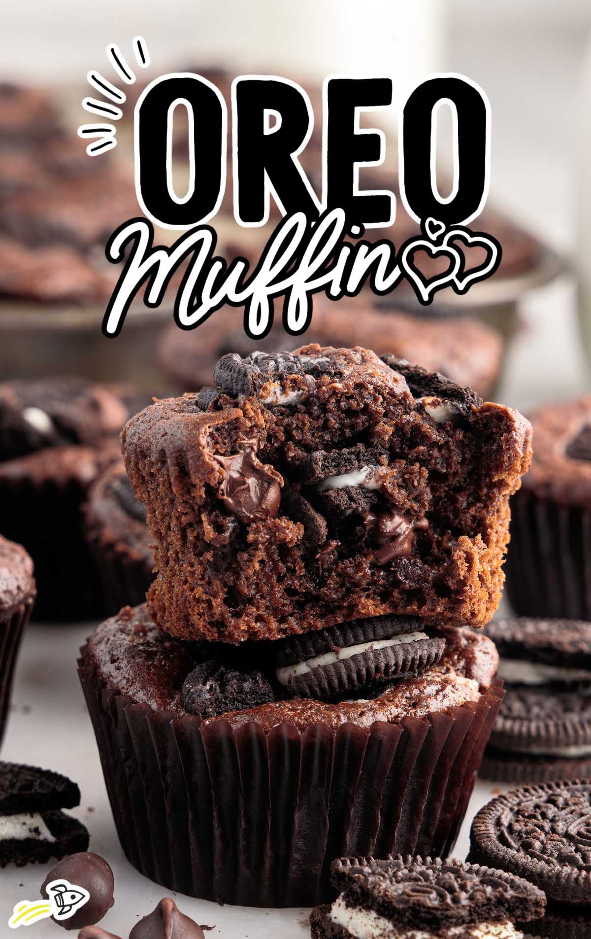 a close up shot of a Oreo Muffin stacked on top of another one with a bite taken out of it