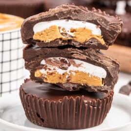 close up shot of Peanut Butter Marshmallow Cups stacked on top of each other with a bite taken out of them on a plate