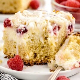 close up shot of a slice of Raspberry Coffee Cake on a plate with a fork grabbing a piece