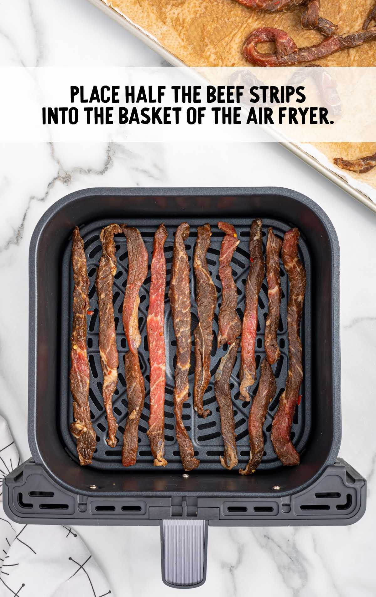 beef strips placed into the air fryer basket