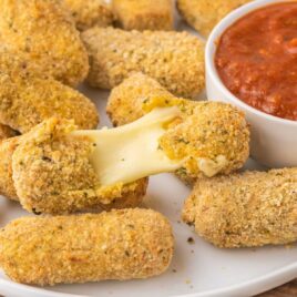 a close up shot of Air Fryer Mozzarella Sticks with one being pulled apart