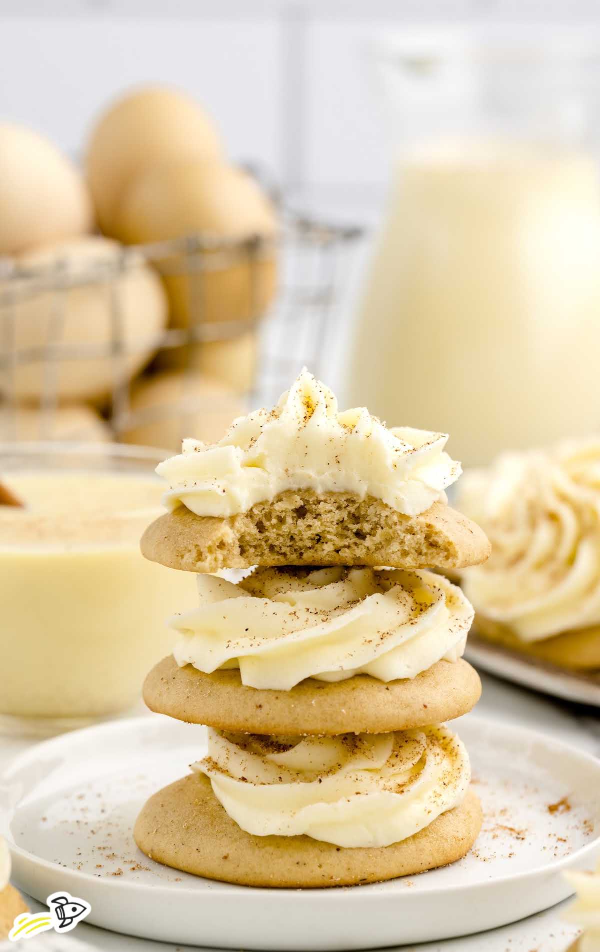 a close up shot of Eggnog Cookies stacked on top of each other with one having a bite taken out it