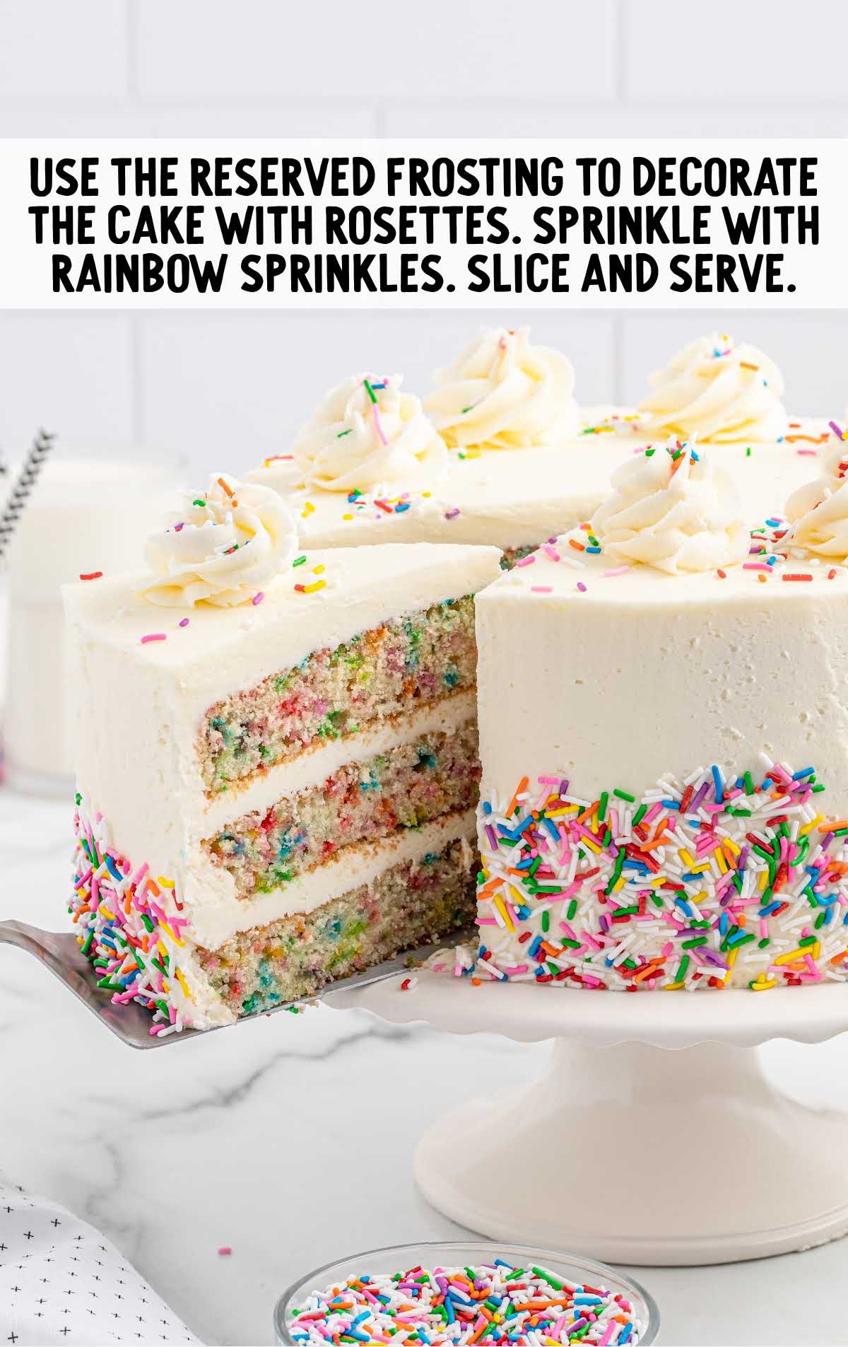 cake topped with frosting and rainbow sprinkles on a cake stand