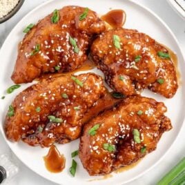 a plate of Honey Garlic Chicken Breasts topped with sesame seeds and green onions