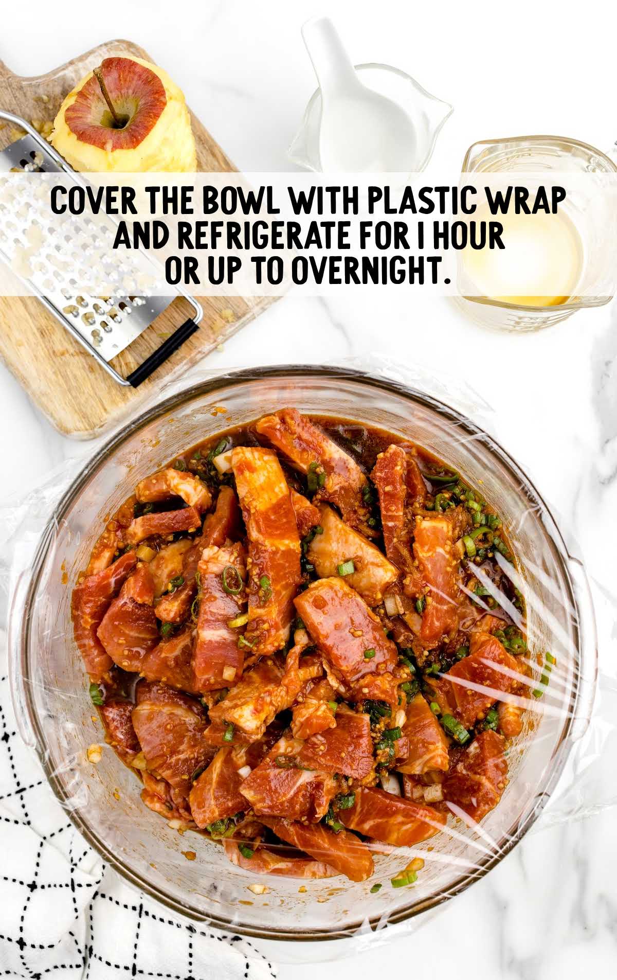 pork marinading in a bowl wrapped in plastic