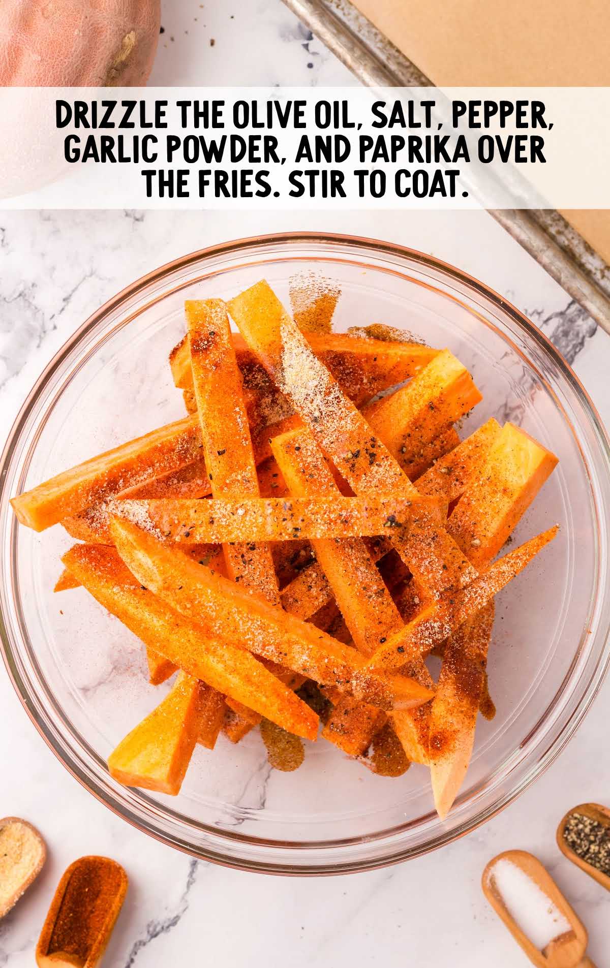 olive oil. salt, pepper, garlic powder, and paprika drizzled over the fries.