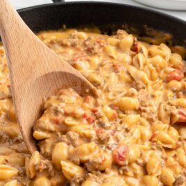 close up shot of Taco Macaroni in a skillet with a large wooden spoon