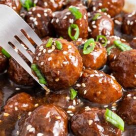 close up shot of Teriyaki Meatballs in a bowl with a fork grabbing one of them