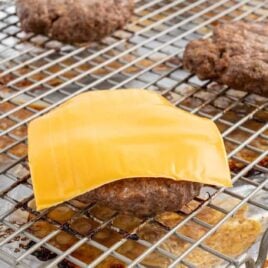 close up shot of Hamburgers topped with a slice of American cheese on a baking rack