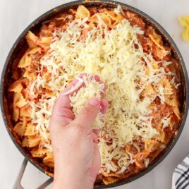 overhead shot of Bow Tie Lasagna in a skillet with cheese garnished on top