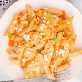 overhead shot of a plate of Buffalo Chicken Pasta topped with blue cheese with a fork