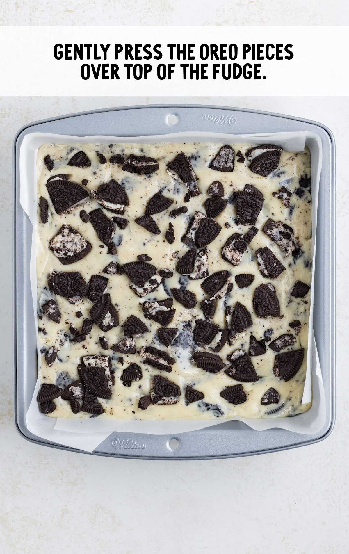 oreos sprinkled on top of the fudge mixture in a pan