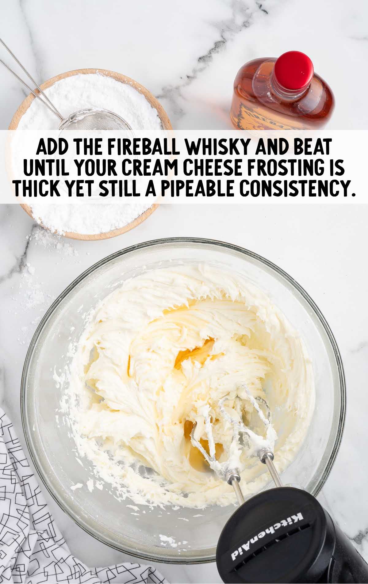 Fireball cinnamon whisky added to the frosting ingredients in a bowl