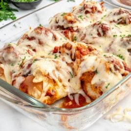 close up shot of garlic bread meatballs garnished with parsley in a baking dish