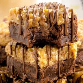 close up shot of German Chocolate Brownies stacked on top of each other on a tray with one having a bite taken out of it