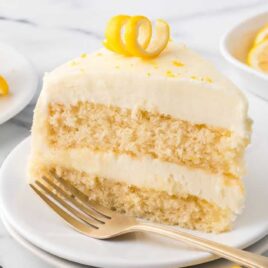 a slice of Lemon Velvet Cake topped with lemon zest on a plate with a fork