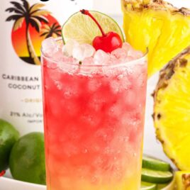 a close up shot of Malibu Cocktail garnished with a cherry, sliced pineapple, and a slice of lime