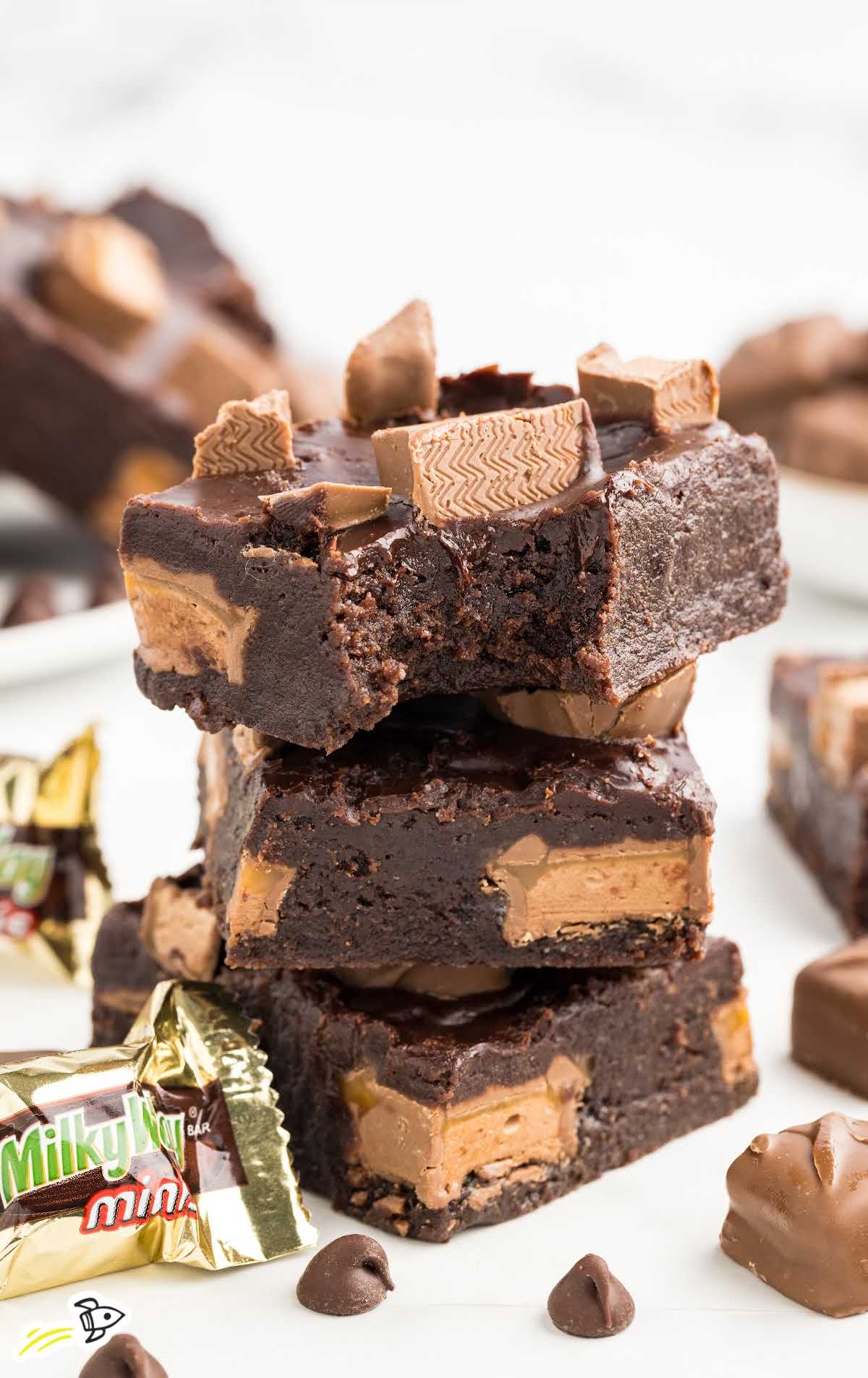 a close u shot of Milky Way Brownies stacked on top of each other with one having a bite taken out of it