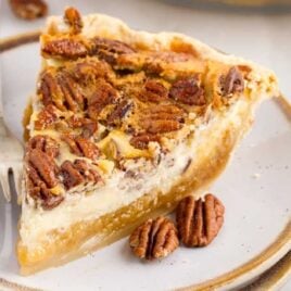 a slice of Pecan Cheesecake Pie on a plate with a fork