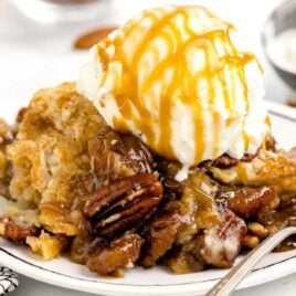 a close up shot of Pecan Dump Cake on a plate topped with ice cream