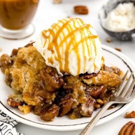 a close up shot of Pecan Dump Cake on a plate topped with ice cream