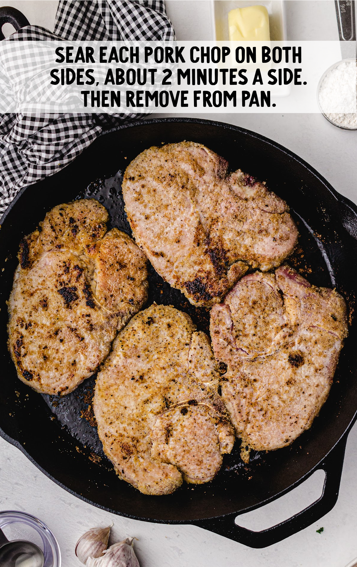 Four pork chops searing in a hot iron skillet.