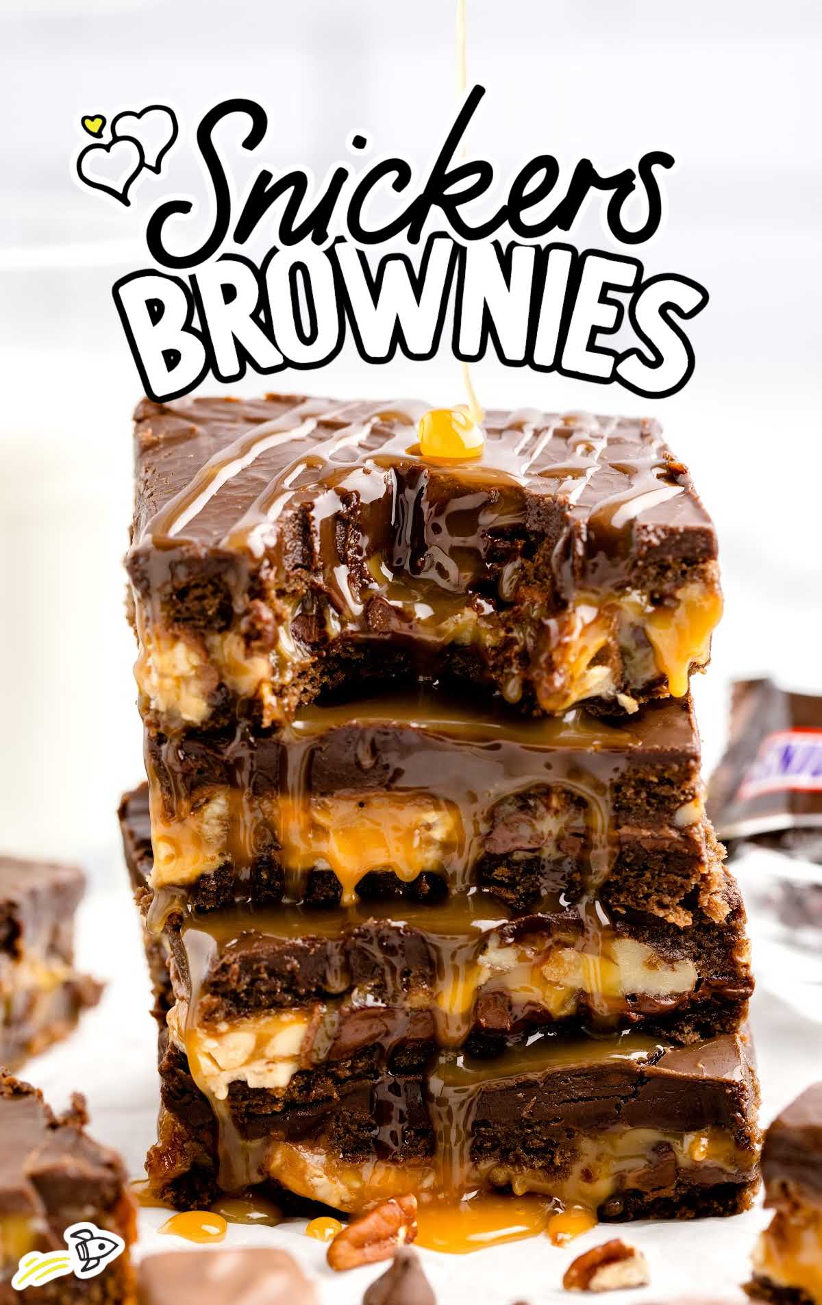 a close up shot of Snickers Brownies stacked on top of each other with one having a bite taken out of it