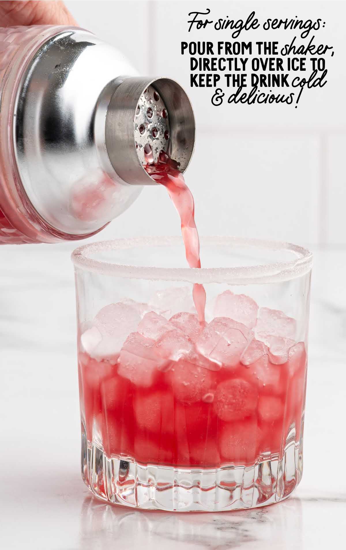 Pouring bright red cranberry Christmas cocktail from a shaker over ice into a glass to keep it cold and refreshing.
