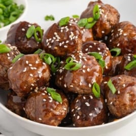 Bowl of teriyaki meatballs coated in rich sauce and sprinkled with sesame seeds
