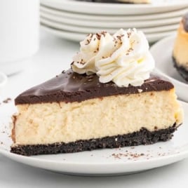 Decadent Baileys cheesecake with a thick chocolate ganache layer, whipped cream swirls, and chocolate shavings.