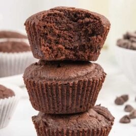 a close upshot of Brownie Muffins stacked on top of each other with one having a bite taken out of it