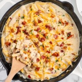 chicken penne garnished with parsley and bacon bits in a skillet