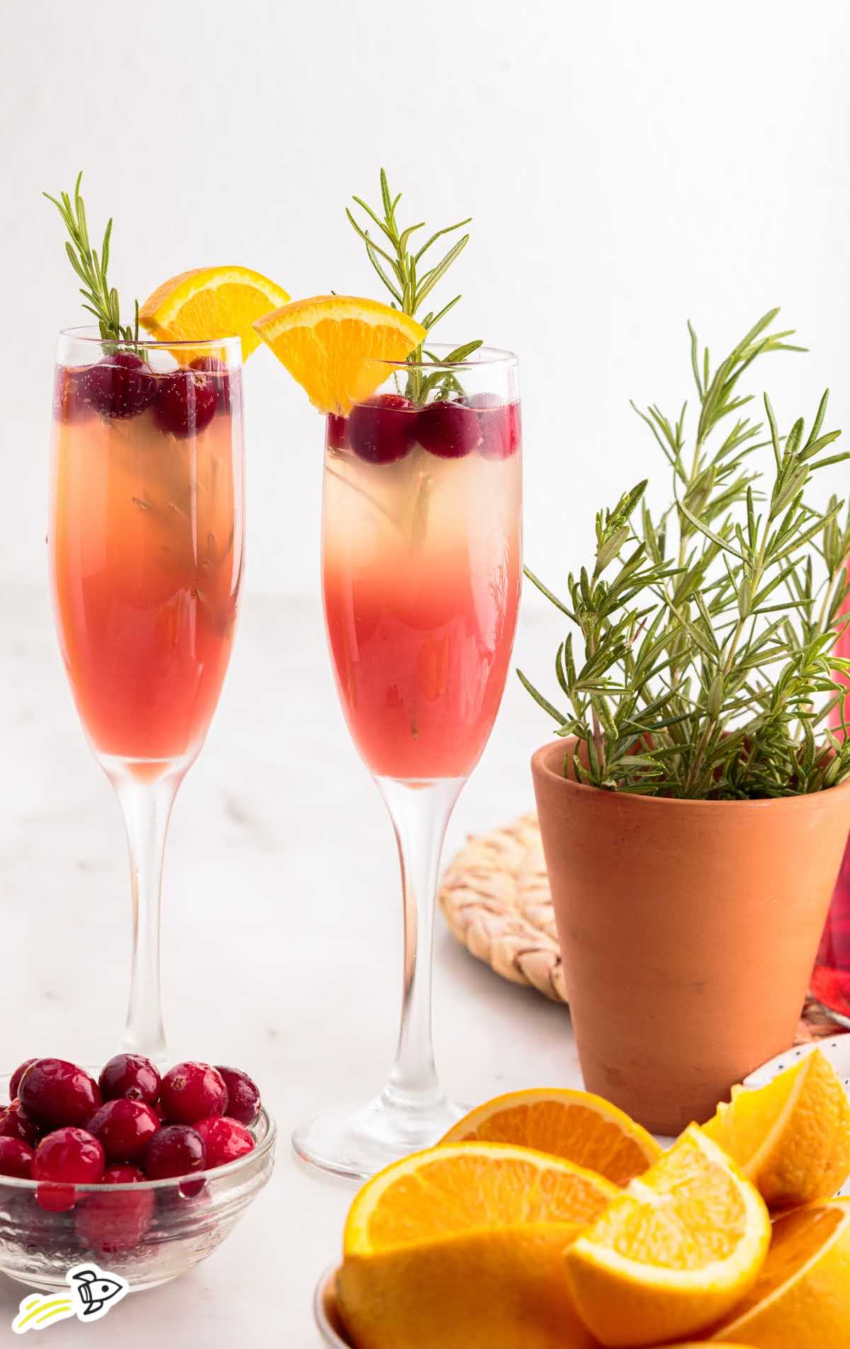 glasses of Cranberry Orange Mimosa garnished with a slice of orange and cranberries