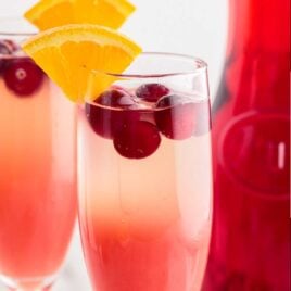 glasses of Cranberry Orange Mimosa garnished with a slice of orange and cranberries