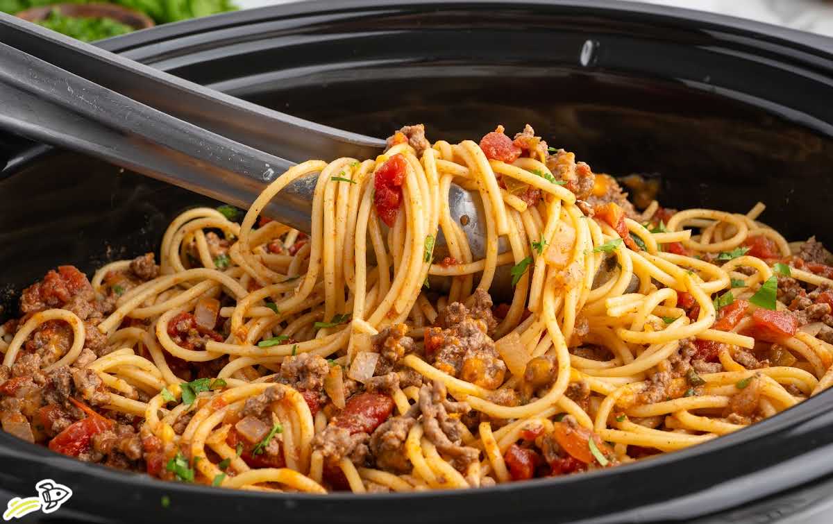 Slow cooker taco spaghetti stirred inside a crockpot before serving
