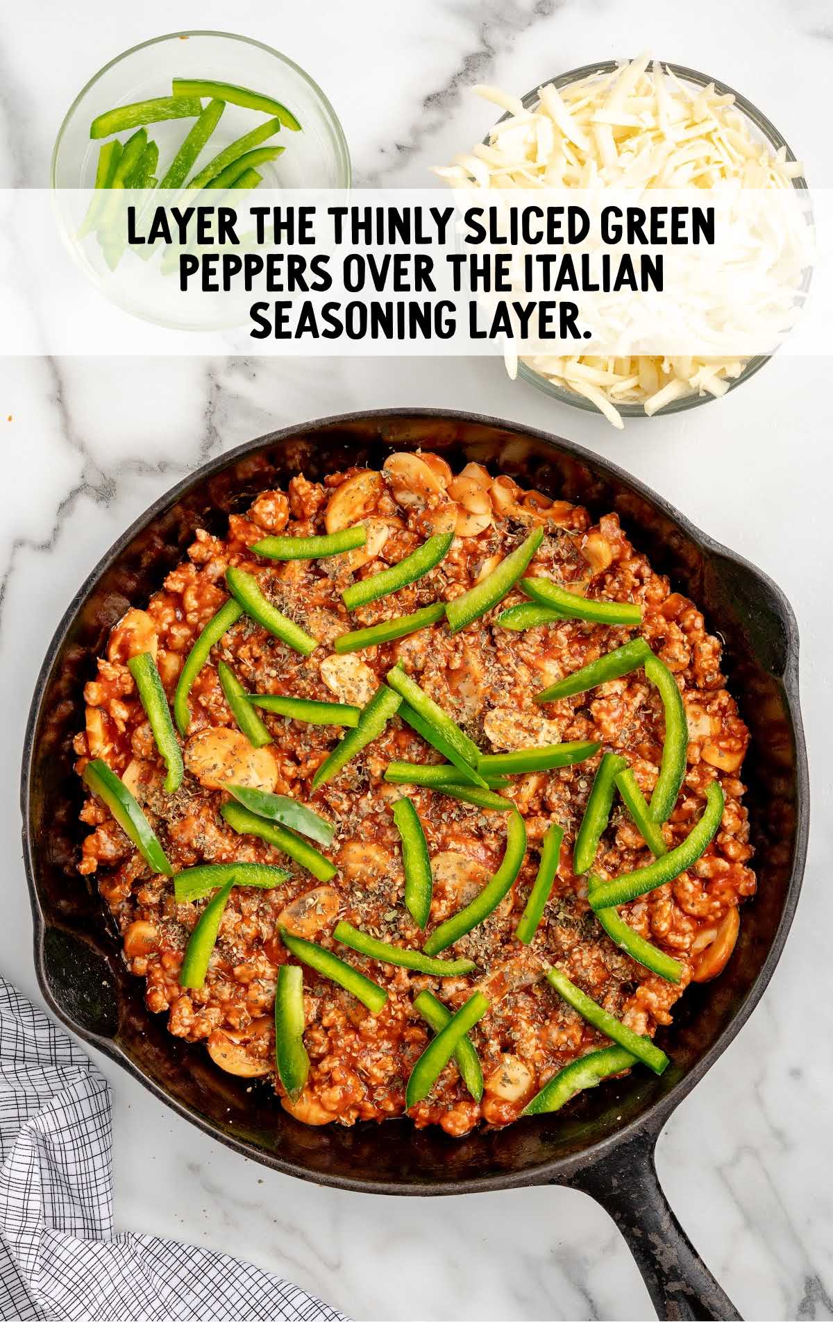 sliced green peppers placed over the Italian seasoning layer in a skillet