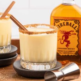 a glass of Fireball Eggnog sprinkled with cinnamon and garnished with a cinnamon stick