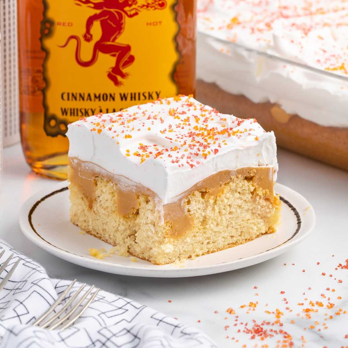 close up shot of a cake on a plate with a fireball bottle in the background
