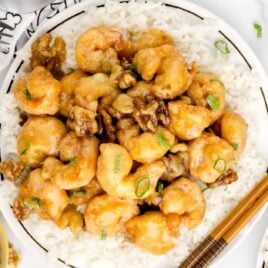 overhead shot of a plate of Honey Walnut Shrimp garnished with scallions and served over white rice