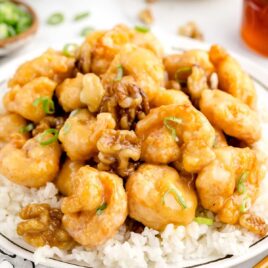 close up shot of a plate of Honey Walnut Shrimp garnished with scallions and served over white rice