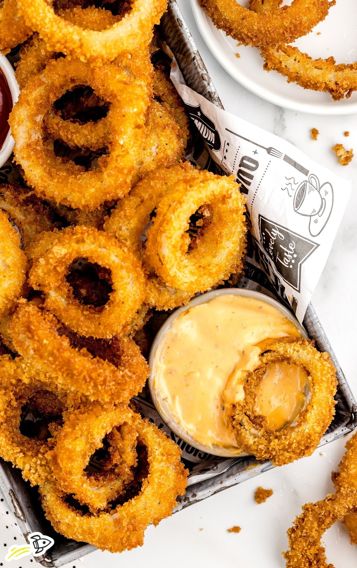 a bunch of Onion Rings dipped into a bowl of sauce