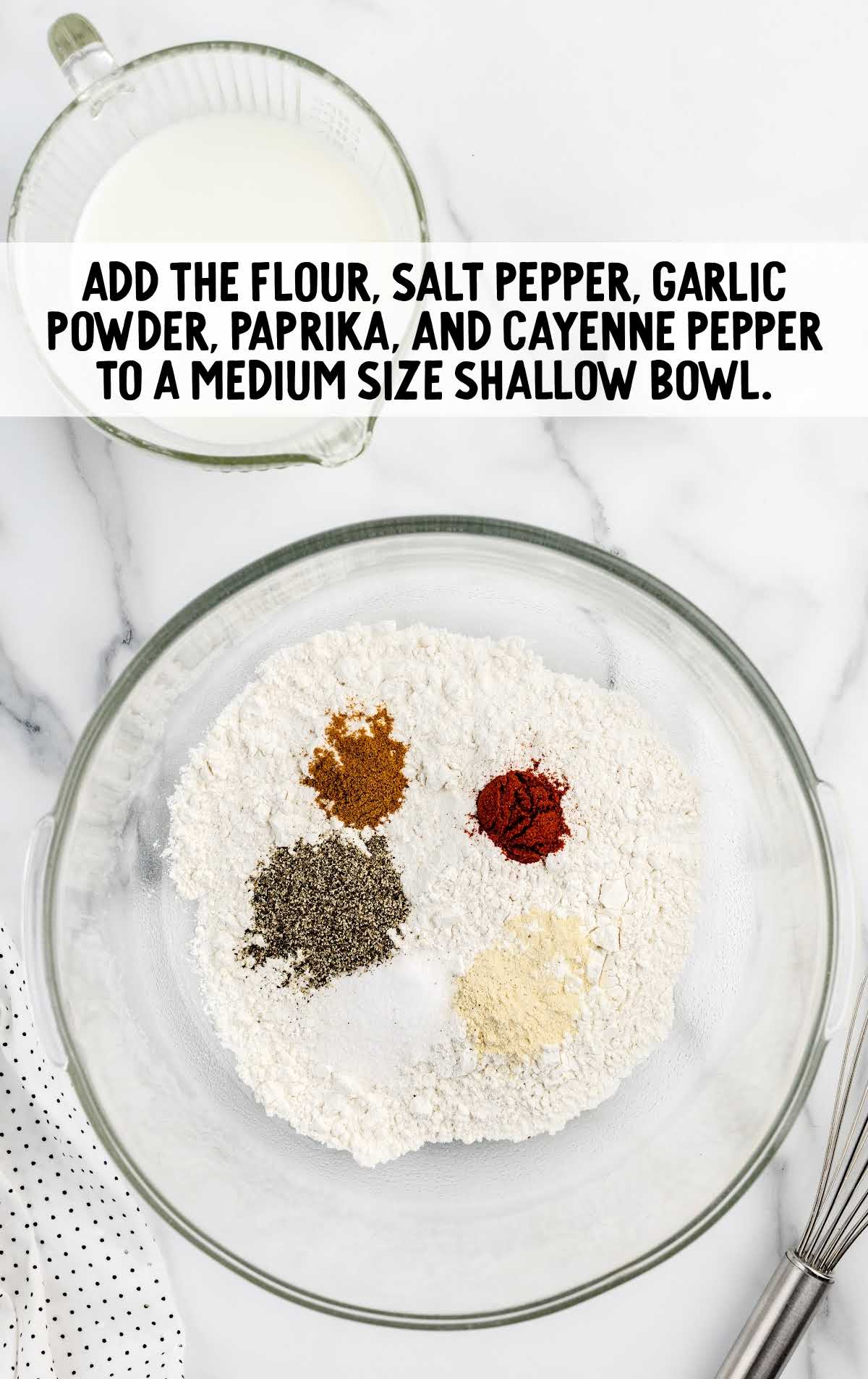 flour, salt pepper, garlic powder, paprika, and cayenne pepper whisked into a flour mixture in a bowl