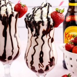 close up shot of Strawberry Mudslides topped with chocolate sauce, whipped cream, and a strawberry